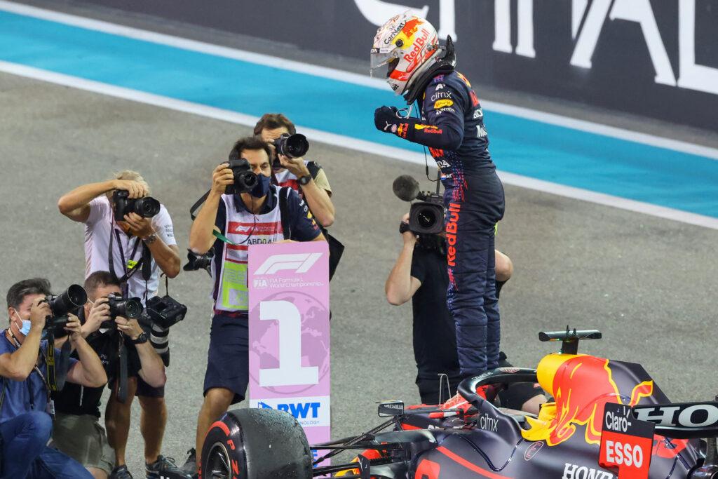 Max Verstappen celebrating on top of his Red Bull f1 car after winning the 2021 Abu Dhabi grand prix.
