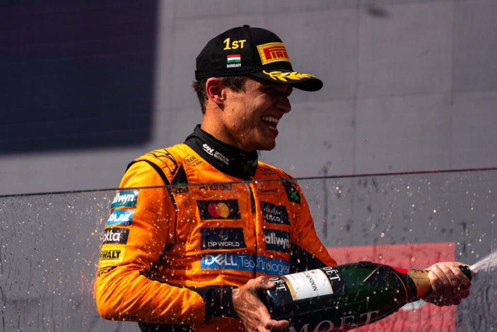 Lando Norris of McLaren sprays champagne on the podium