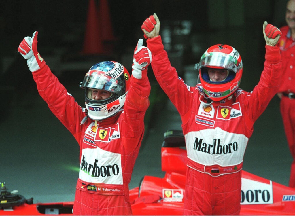 Ferrari drivers Eddie Irvine and Michael Schumacher celebrating at the 1999 Malaysian Grand Prix