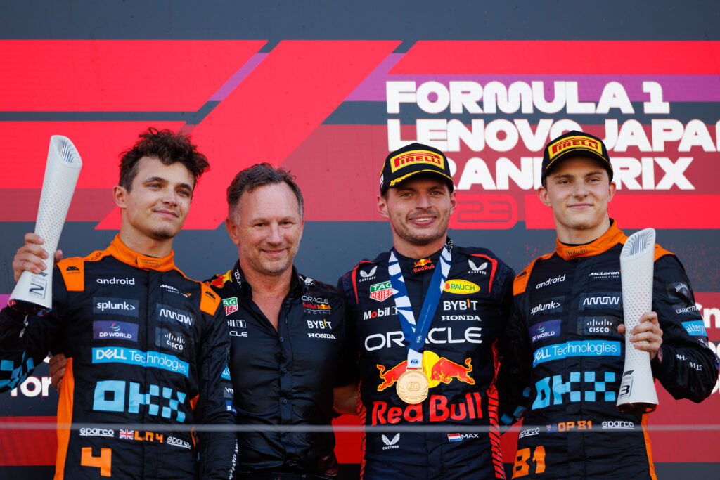 McLaren drivers Lando Norris (far left) and Oscar Piastri (far right) alongside Red Bull team principal Christian Horner (centre left) and driver Max Verstappen (centre right) on the podium at the 2023 Japanese Grand Prix
