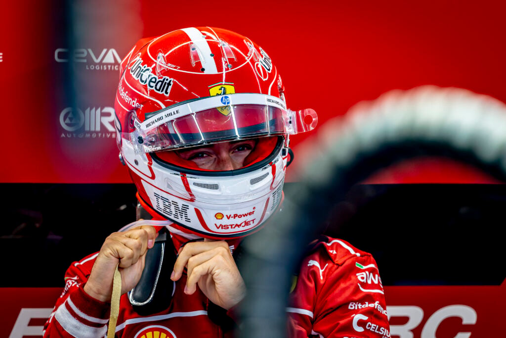 Charles Leclerc puts on his helmet in the Ferrari garage