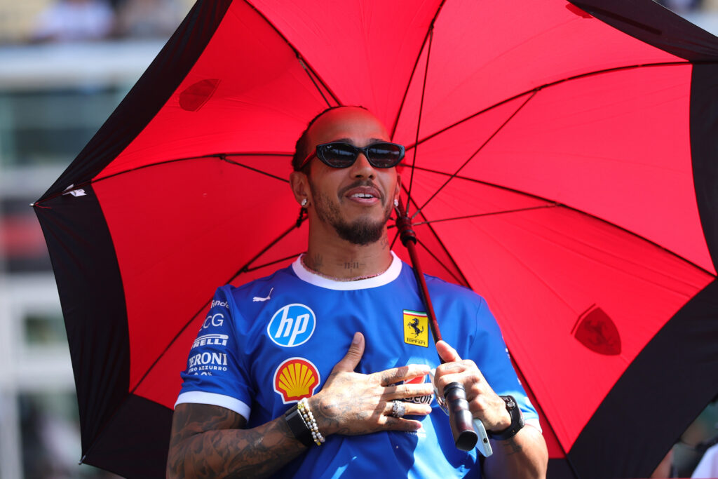 Ferrari driver Lewis Hamilton with his hand on his heart, holding an umbrella at the 2025 Formula 1 Italian Grand Prix