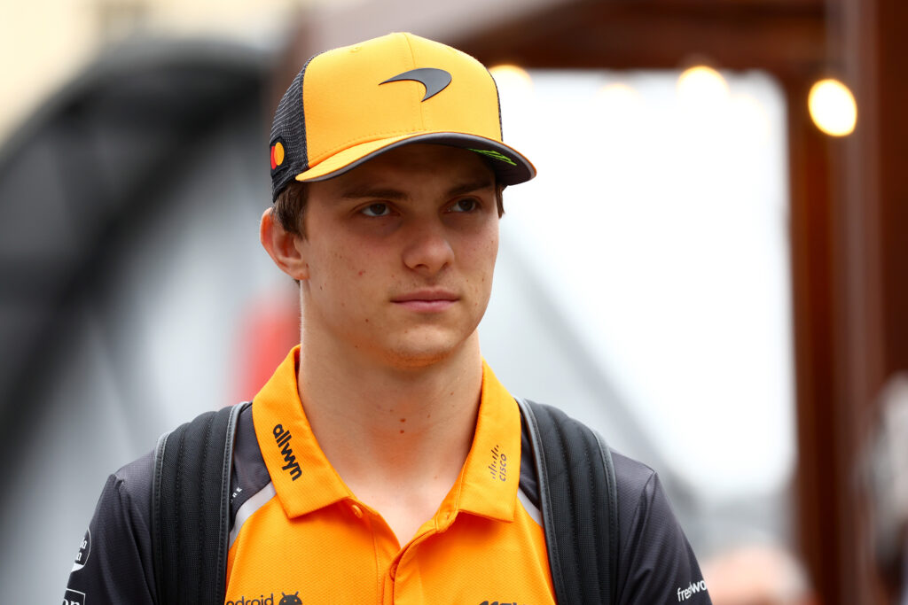 McLaren driver Oscar Piastri arrives in the Baku paddock before practice for the 2025 F1 Azerbaijan Grand Prix with an inset of Red Bull motorsport adviser Helmut Marko in Hungary