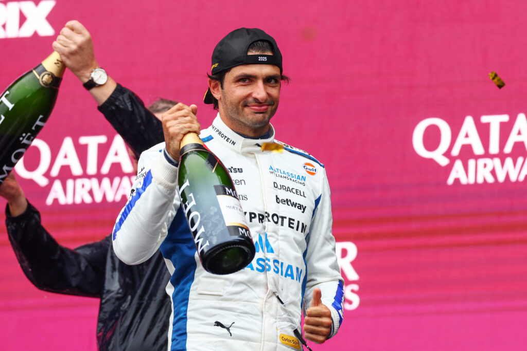 Williams driver Carlos Sainz holding a bottle of champagne on the podium after the 2025 Formula 1 Azerbaijan Grand Prix