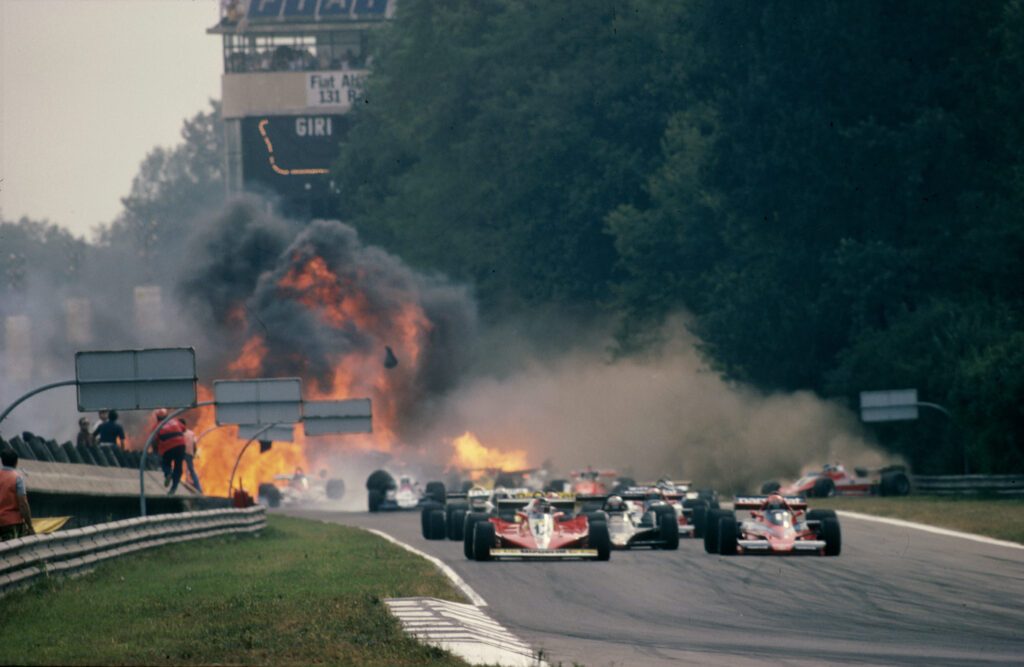 Formula 1 cars drive away from a fire ball, after an incident further back in the grid at the 1978 Italian Grand Prix