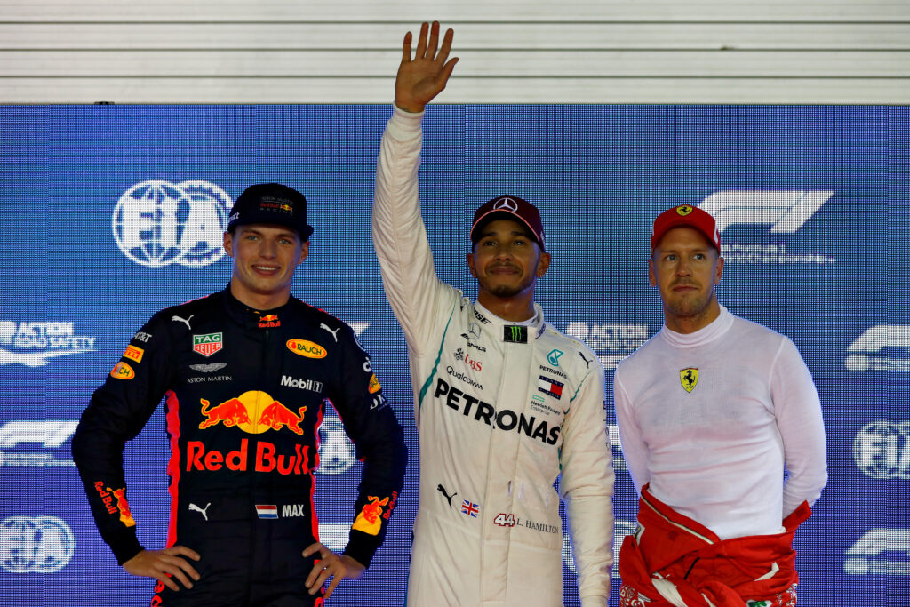 Lewis Hamilton posing with Max Verstappen and Sebastian Vettel after qualifying for the 2025 Singapore Grand Prix.