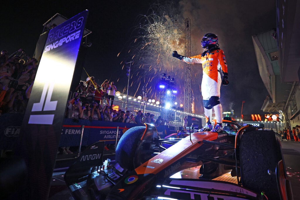 Lando Norris stands on his McLaren as fire works explode in the background after winning the 2024 Singapore Grand Prix