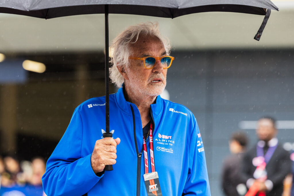Flavio Briatore of Alpine shelters under an umbrellla at the British Grand Prix