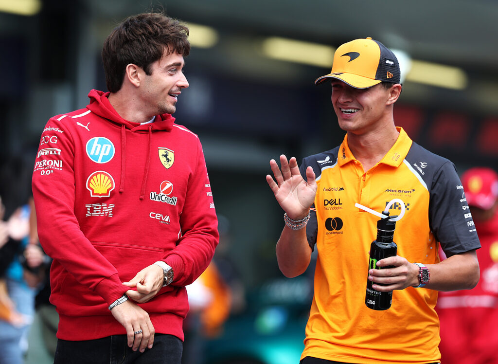 Charles Leclerc of Ferrari laughs with Lando Norris of McLaren