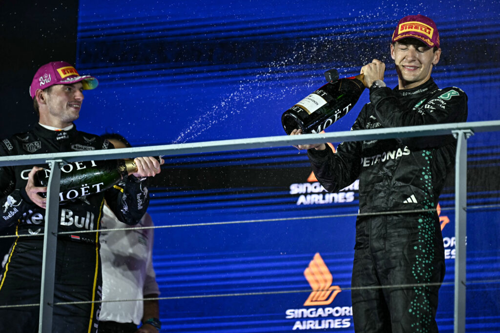 Red Bull's Max Verstappen sprays George Russell with champagne after the Mercedes driver won the 2025 F1 Singapore Grand Prix