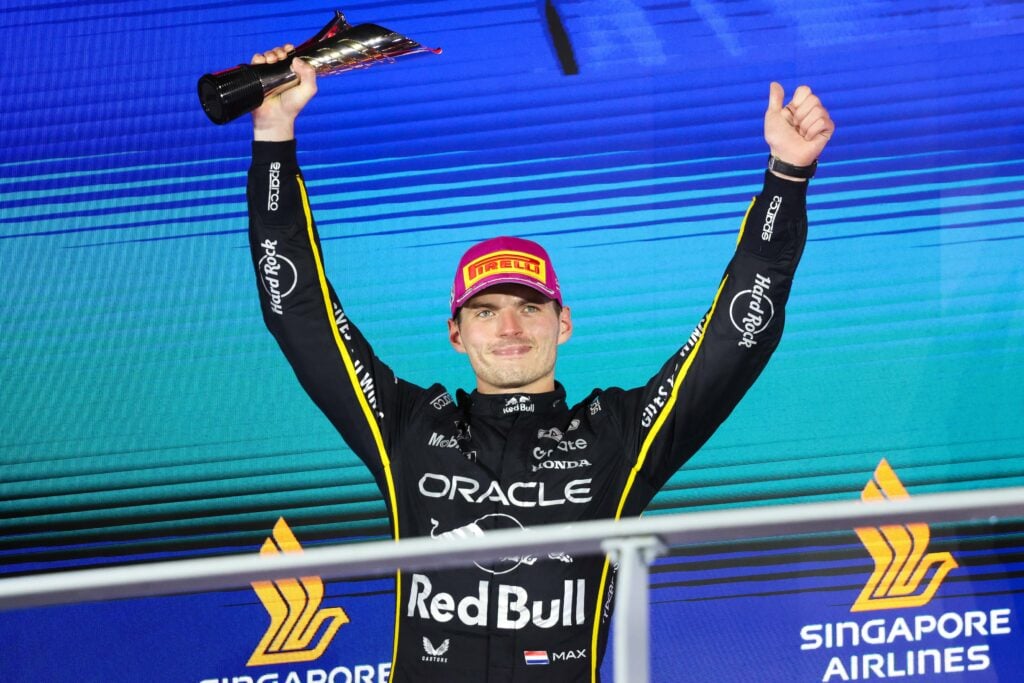 Red Bull driver Max Verstappen celebrating with his trophy on the podium after the 2025 Formula 1 Singapore Grand Prix