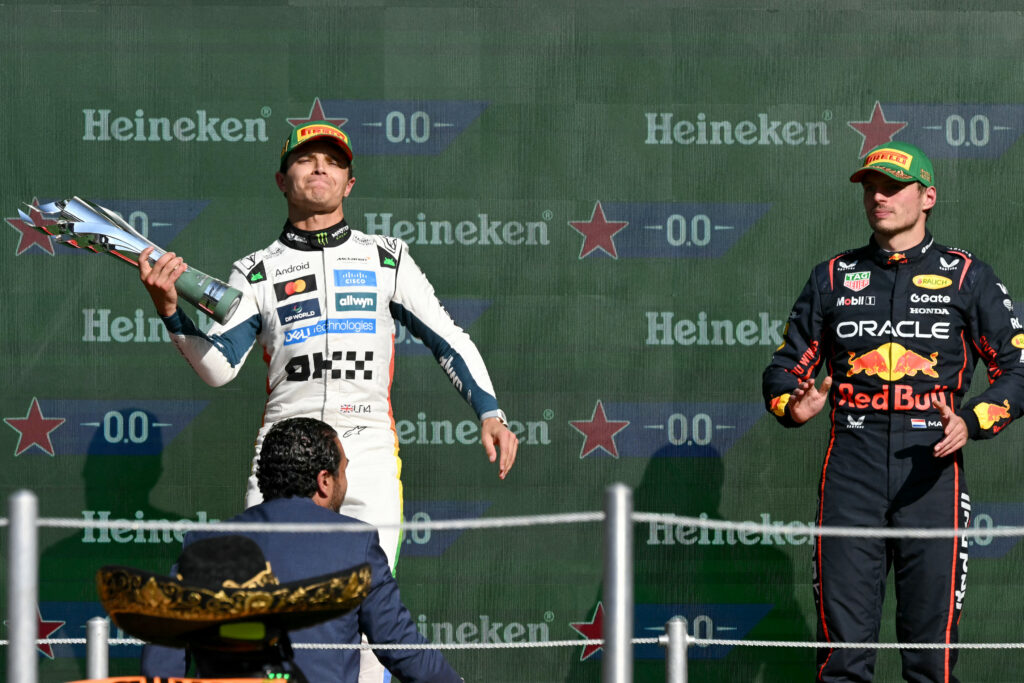 McLaren's Lando Norris lifts his trophy to celebrate winning the 2025 F1 Mexico City Grand Prix as Red Bull's Max Verstappen applauds
