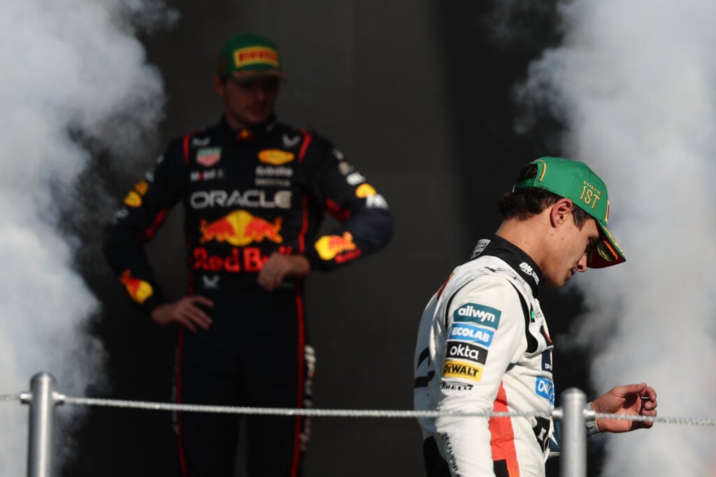 Red Bull driver Max Verstappen looks on as McLaren's Lando Norris celebrates winning the 2025 F1 Mexico City Grand Prix on the podium