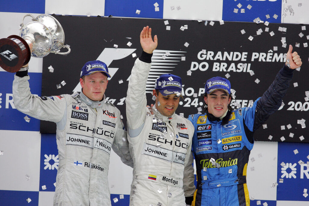 McLaren drivers Kimi Raikkonen and Juan Pablo Montoya celebrating on the podium with Renault driver Fernando Alonso at the 2005 Formula 1 Brazilian Grand Prix