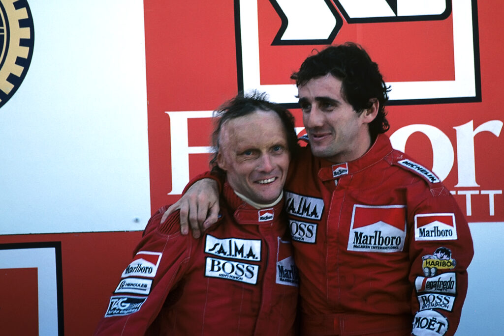 McLaren drivers Niki Lauda and Alain Prost embrace on the podium at the 1984 Portuguese Grand Prix