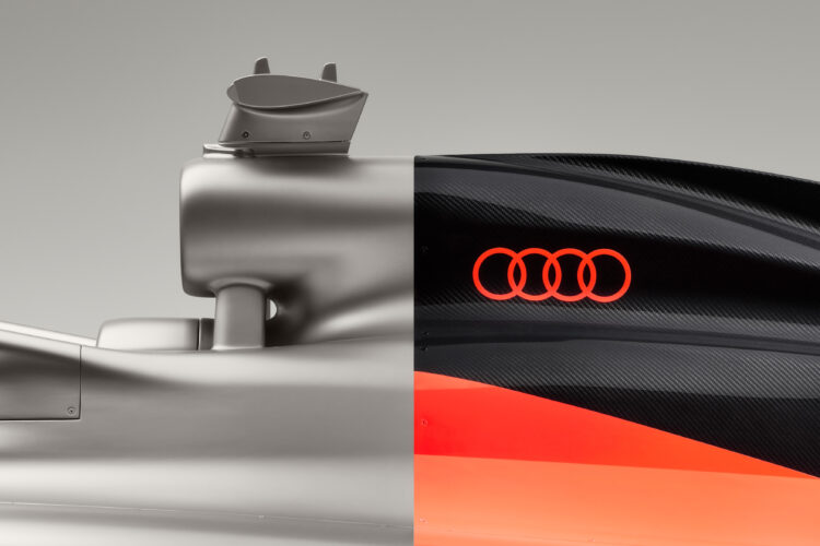 Close-up side image of the Audi R26 Formula 1 car, which shows a titanium first half and black and red back of the car, which features the Audi logo