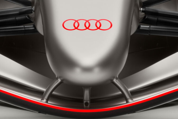 Close-up image of the nose tip and front wing of Audi's R26 F1 car. It is silver with some red detailing on the logo and edge of front wing