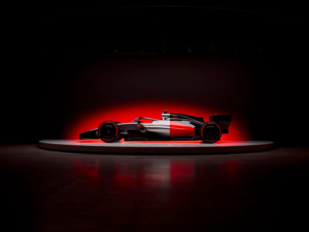 Side profile of the Audi R26 Formula 1 car infront of a glowing red background