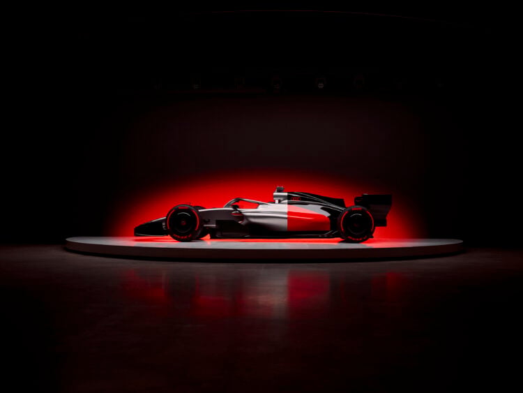Side profile of the Audi R26 Formula 1 car infront of a glowing red background