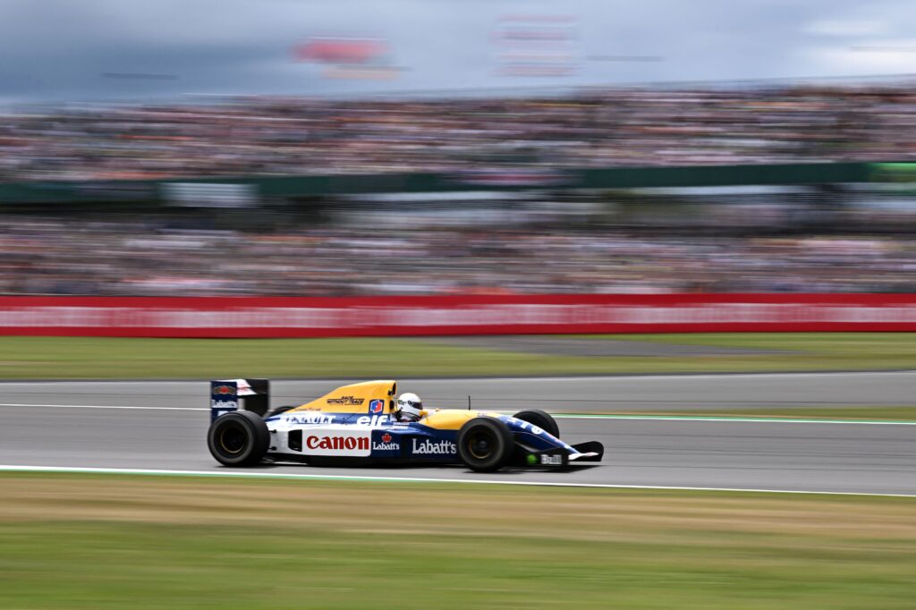 Sebastian Vettel driving Nigel Mansell's 1992 Williams speeds past the grandstands at the British Grand Prix