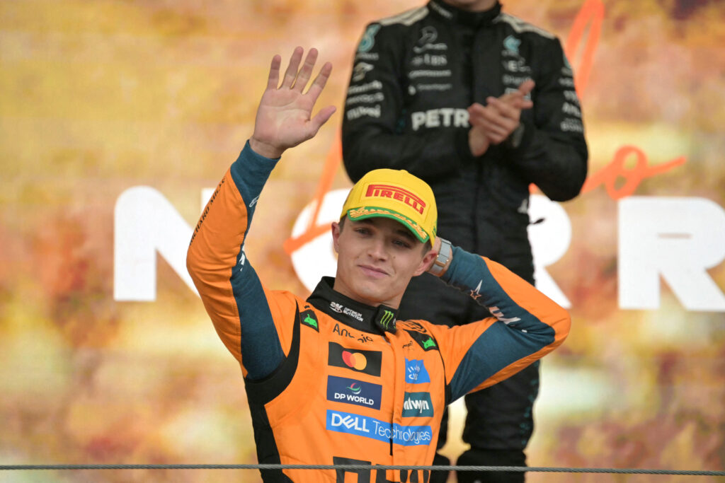 McLaren driver Lando Norris waving from the podium at the 2025 Formula 1 Sao Paulo Grand Prix