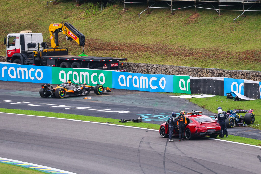 Marshals removing Oscar Piastri's stricken McLaren F1 car after his crash at the Brazilian Grand Prix, with Franco Colapinto's crashed Alpine to the right of it.