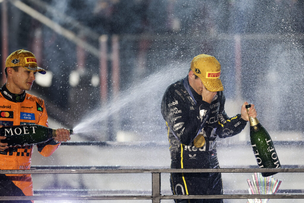 McLaren driver Lando Norris spraying Red Bull driver Max Verstappen with champagne on the podium at the 2025 Formula 1 Las Vegas Grand Prix