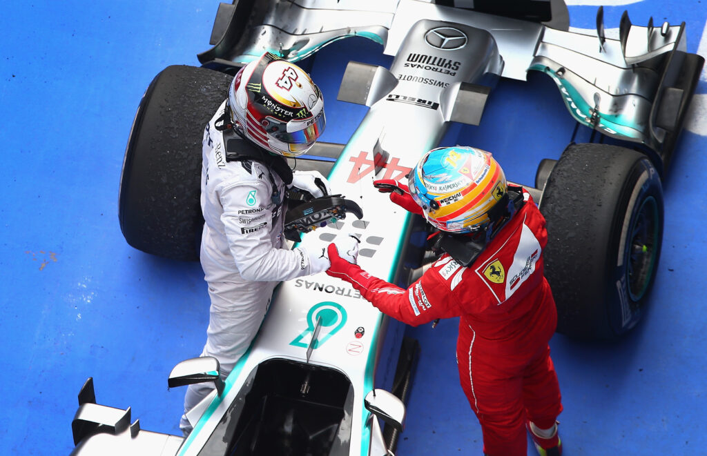 Fernando Alonso, in Ferrari colours, shakes hands with Lewis Hamilton, then of Mercedes, in parc ferme
