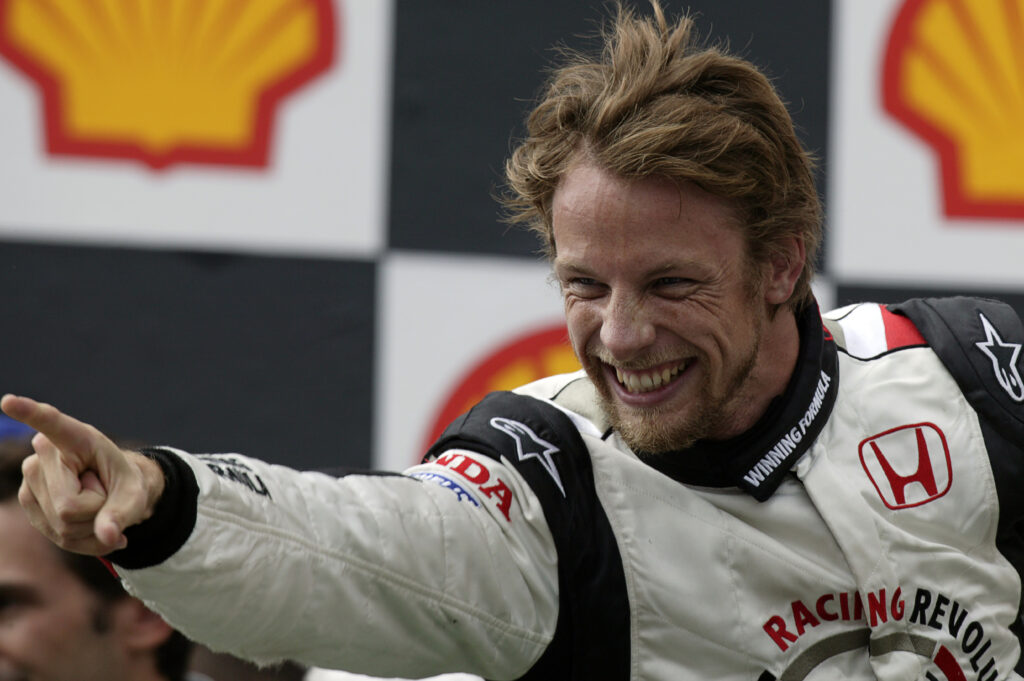 Jenson Button smiles and points to his team after winning the 2006 Hungarian Grand Prix