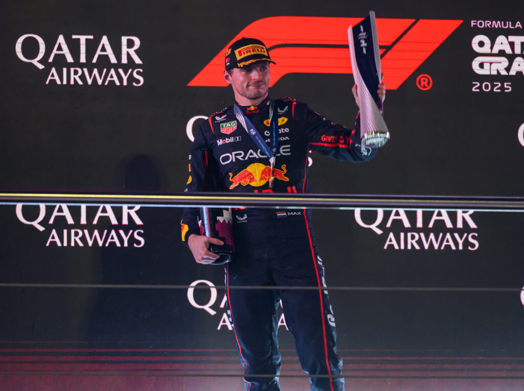 Red Bull Racing driver Max Verstappen lifting a trophy on the podium at the 2025 Formula 1 Qatar Grand Prix