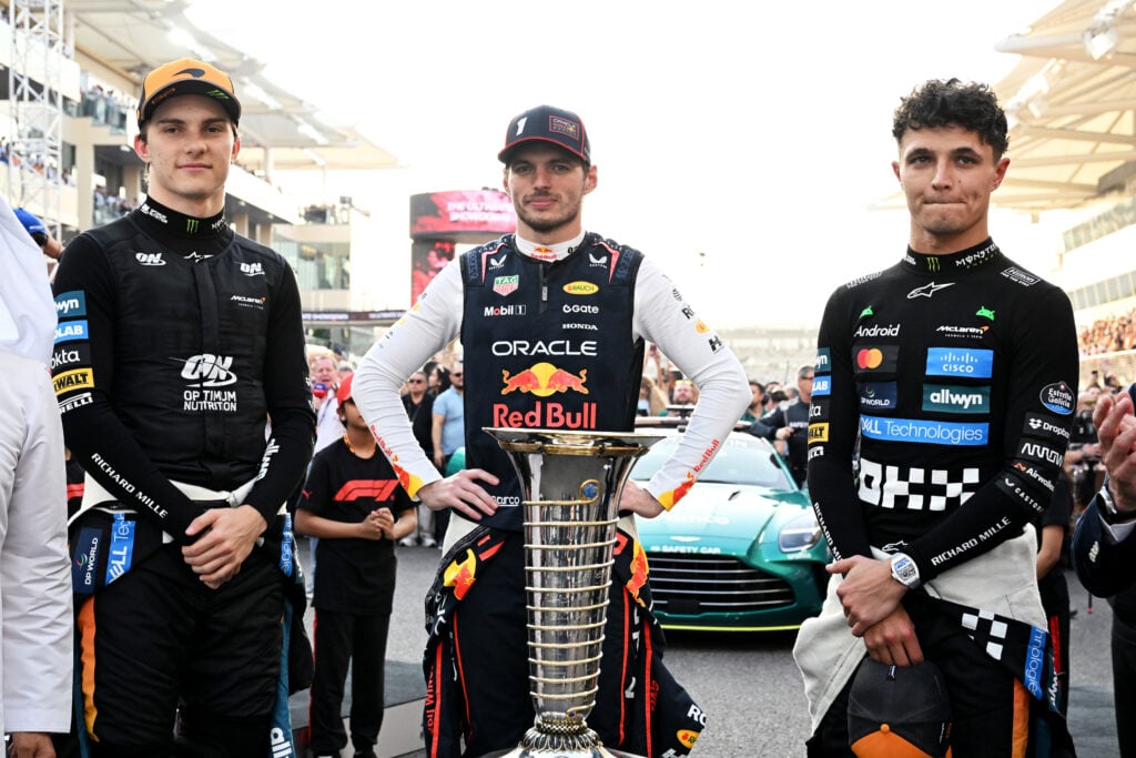 McLaren's Oscar Piastri and Lando Norris and Red Bull's Max Verstappen pose with the championship trophy before the 2025 F1 Abu Dhabi Grand Prix