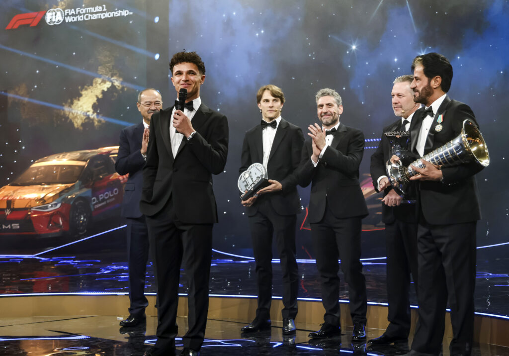 Oscar Piastri looks on as McLaren teammate Lando Norris receives the 2025 F1 drivers' championship trophy