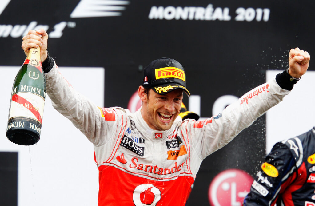 Jenson Button of McLaren celebrating his win at the 2011 Canadian Grand Prix with a bottle of champagne in his hands.