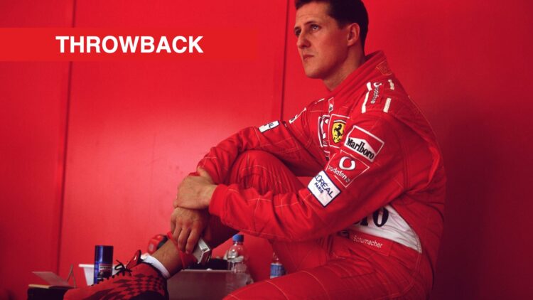 Michael Schumacher sitting on a desk inside the Ferrari garages at the 2002 Malaysian Grand Prix.