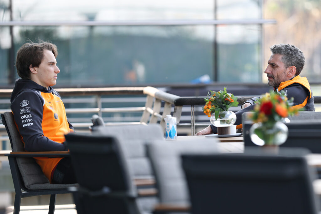 McLaren driver Oscar Piastri sitting in a meeting with team principal Andrea Stella at the 2025 Formula 1 Chinese Grand Prix