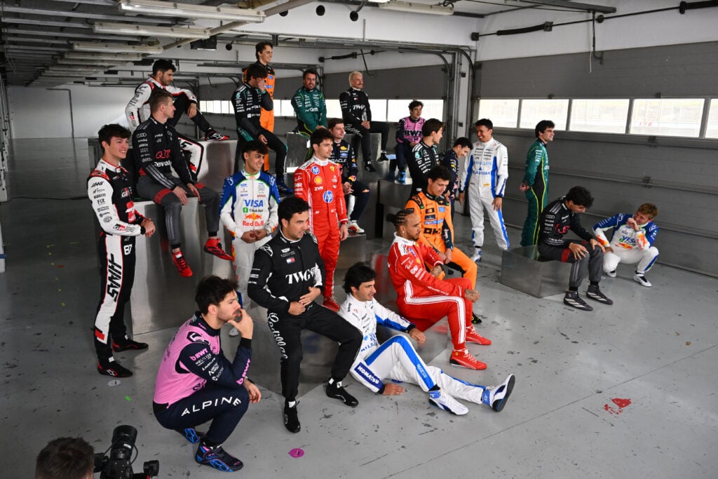 F1 drivers including Oscar Piastri, Lando Norris and Max Verstappen pose for the official 2026 F1 grid photo in a garage in Bahrain