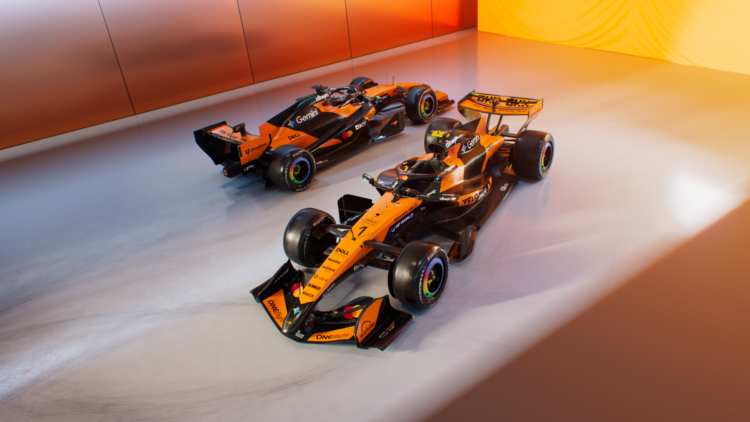 Image showing the two 2026 McLaren MCL40 cars on a white floor with a yellow and orange background
