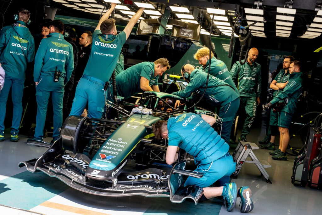 Aston Martin mechanics work on Fernando Alonso's car in the garage