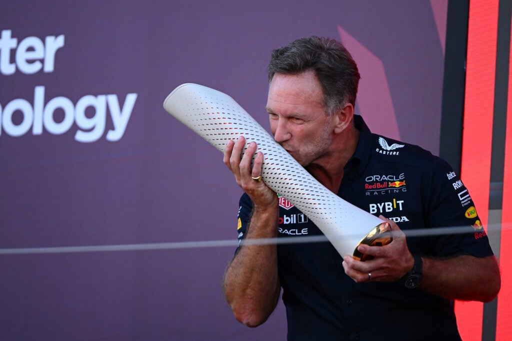 Christian Horner kisses an F1 trophy on the podium for Red Bull