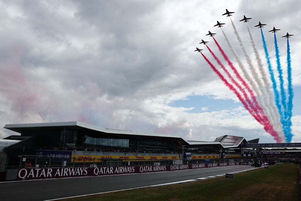 The Red Arrows soar over the start line, with their iconic red, white and blue smoke ahead of the beginning of the 2025 British Grand Prix