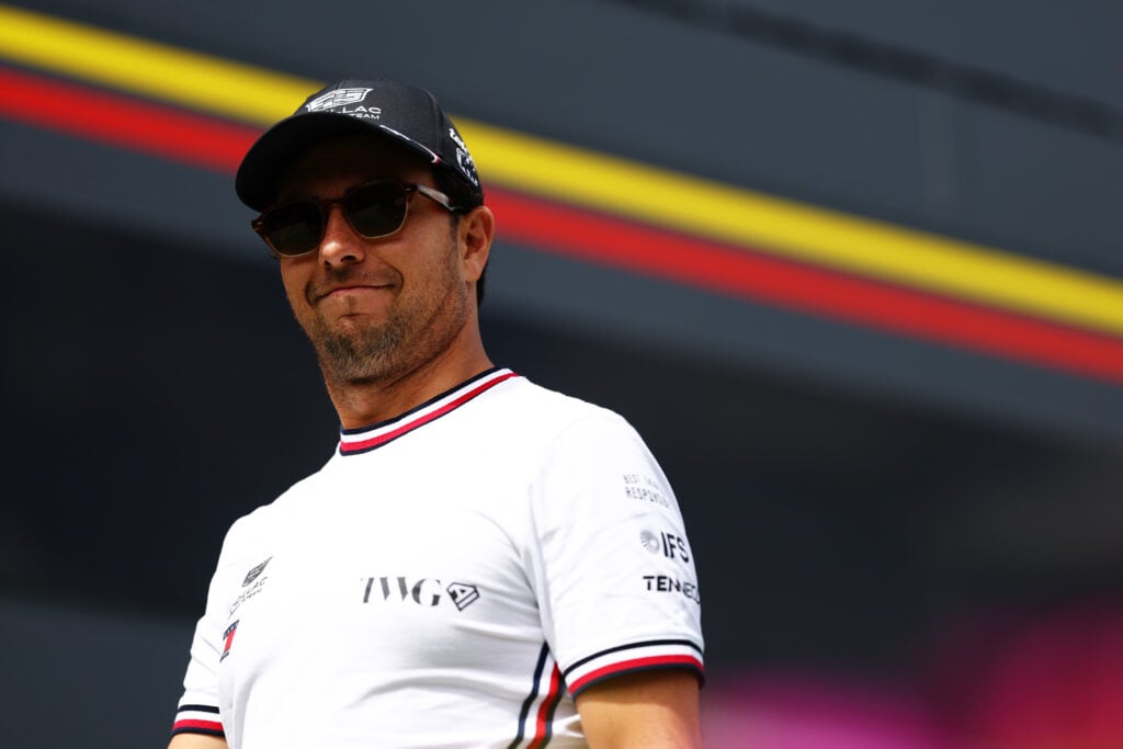 Sergio Perez smiling at the camera as he walks through the 2026 Barcelona Grand Prix paddock.